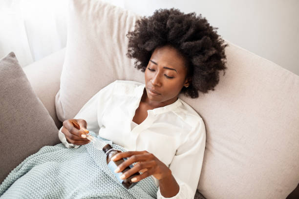 istock Woman taking cough syrup on sofa at home. 1356152989