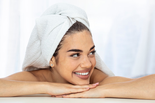 Cosmetology, beauty and spa. perfect woman with white towel on head after shower having toothy smile touch gently healthy shiny clean skin looking at camera, skincare and natural beauty
