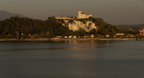Arona, Italy - October 16, 2021: Mediaeval castle viewed across the Italian lake in dawn light