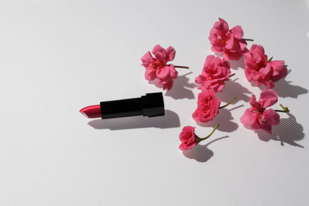 istock Pink lipstick with a pelargonium flowers on a background with a hard shadow. 1356157217