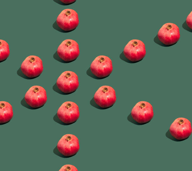 istock Creative pattern made of fresh red pomegranate on the dark green background. Minimal summer fruit layout. 1356157815