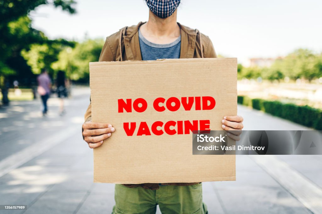 Protester against the Covid19 Vaccine Young man holding a  poster against Covid Vaccination Rebellion Stock Photo