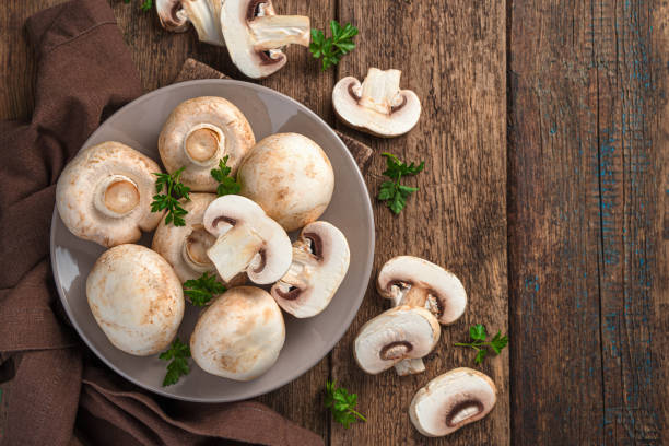 istock Raw mushrooms on a wooden background. Fresh champignons 1356158182