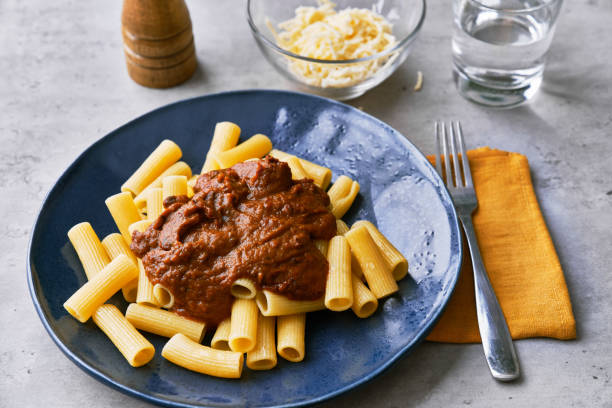 assiette de pâtes italiennes de macaronis à la sauce tomate sur une surface en béton - ingedient photos et images de collection