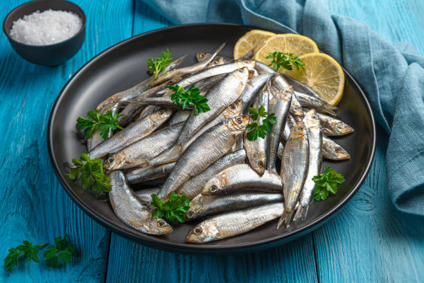 istock Salted sprat with lemon in a plate on a blue background 1356159755