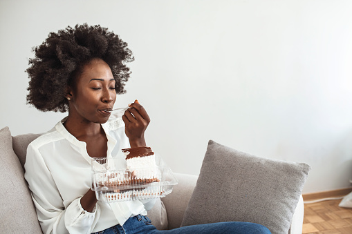 Closeup of woman eating cake. Beautiful girl enjoys eating a cake with chocolate. Pretty young woman eats a sweet cake. food, junk-food, culinary, baking and holidays concept. woman eating chocolate cake with spoon