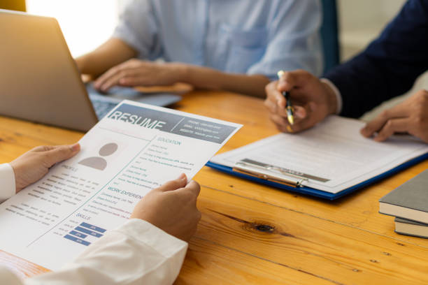Closeup resume in manager's hand when discussing resume with conference room interview, office background applicants, job search, job interview, business ideas. currículum de primer plano en la mano del gerente cuando se discute el currículum con la entrevista de la sala de conferencias, los solicitantes de antecedentes de la oficina, la búsqueda de empleo, la entrevista de trabajo, las ideas de negocios.