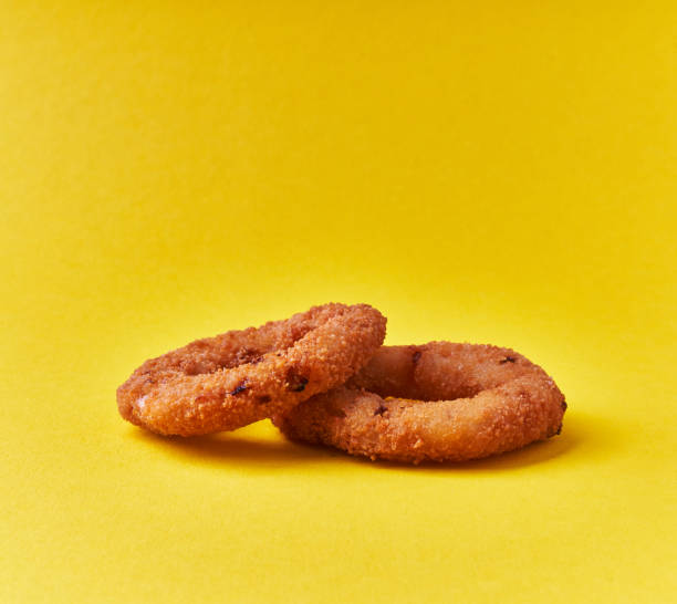 istock Two breaded onion rings on a yellow background 1356162997