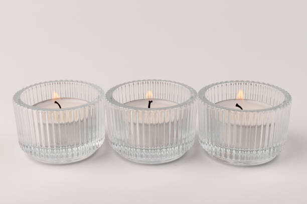 istock Burning tea candles in a glass holder, isolated on white. Space for text 1356163138