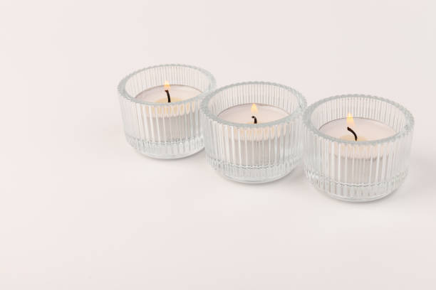 istock Burning tea candles in a glass holder, isolated on white. Space for text 1356163140