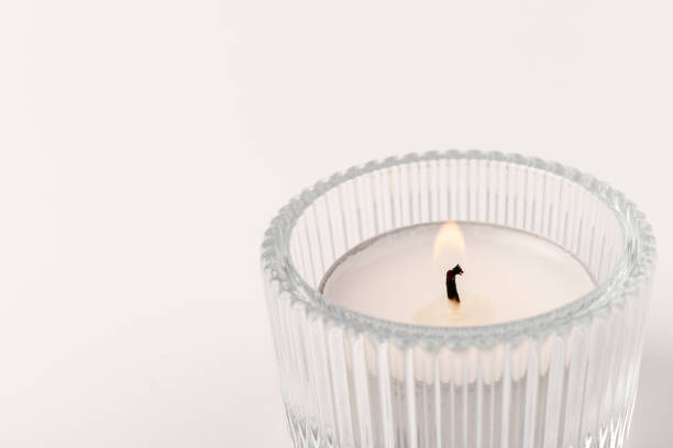 istock Burning tea candles in a glass holder, isolated on white. Space for text 1356163164