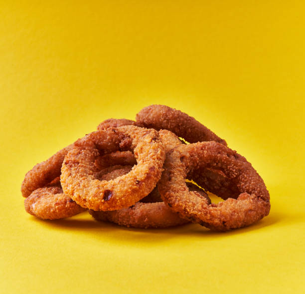 istock Bunch of breaded onion rings on a yellow background 1356163292