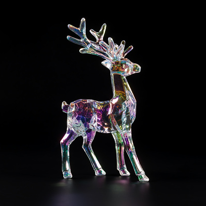 A figurine of a reindeer made of transparent material, colored by light refraction in various colors, on a black background.