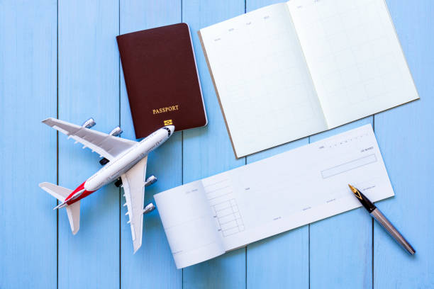 istock check book, pen, mobile smart phone, passport, airplane model and weekly planner notebook isolated on blue wood table background. 1356164577