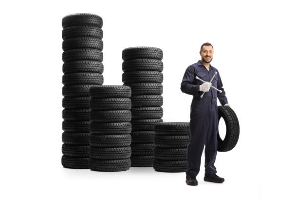 porträt in voller länge eines reifenstapels und eines automechanikers, der einen reifen und einen schraubenschlüssel hält - mechanic auto repair shop manual worker men stock-fotos und bilder