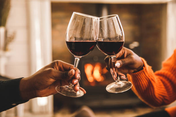 plan rapproché d’un couple portant un toast de fête avec des verres de vin rouge - vin rouge photos et images de collection