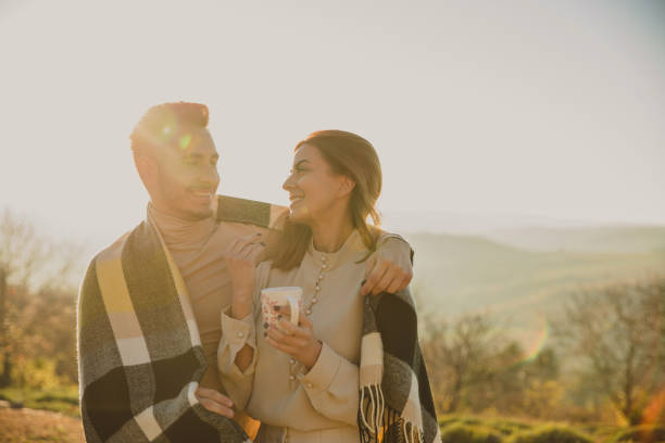 istock Caring young man embracing his girlfriend with a cozy, warm blanket during a walk outside 1356167379