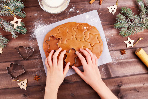 istock Women's hands roll out the dough and make gingerbread cookies with molds. Preparation for Christmas and New Year holidays. 1356167493