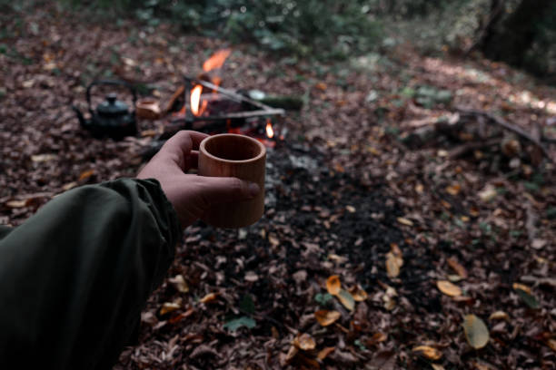 Bushcraft pours water from a bottle into a wood mug.