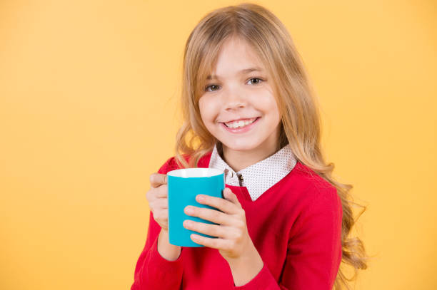 istock Child smile with blue cup on orange background 1356168214