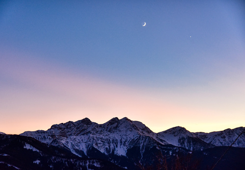 Moon and the planet Venus in the sunset lights over the mountains of the Pusteria valley