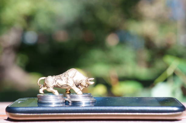 istock Bull figurine with coins on a mobile phone. 1356173191