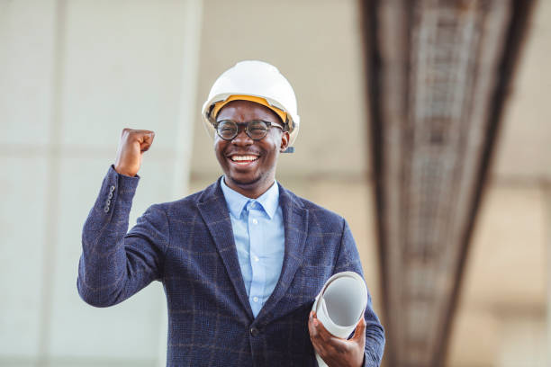 istock Young architect wearing a protective helmet standing on the building background 1356175210
