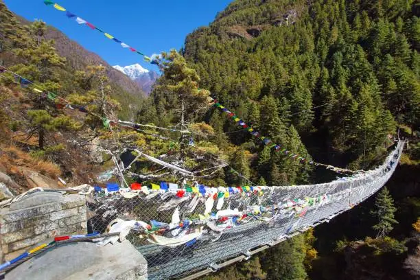 Rope hanging suspension bridge with prayer flags in Nepal Himalayas under Namche Bazar above Dudh Koshi Nadi river, Mount Everest base camp trek