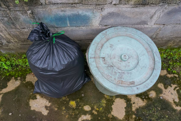 istock Black plastic bag filled with trash near the trash can 1356177308