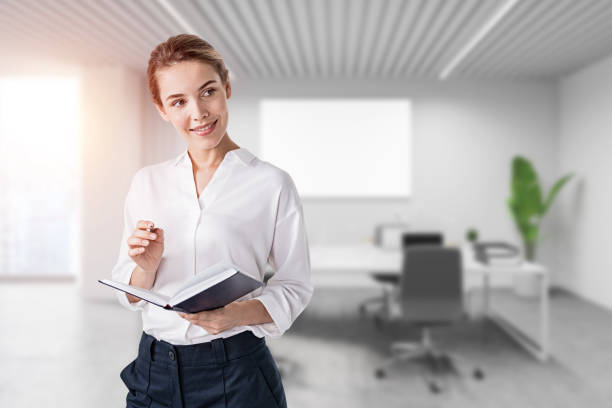 istock Smiling young businesswoman with notebook in office 1356178117