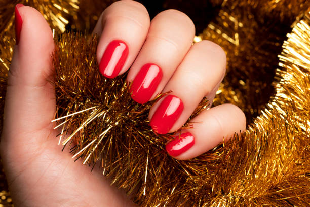 istock Hand with red nails with golden tinsel 1356178260