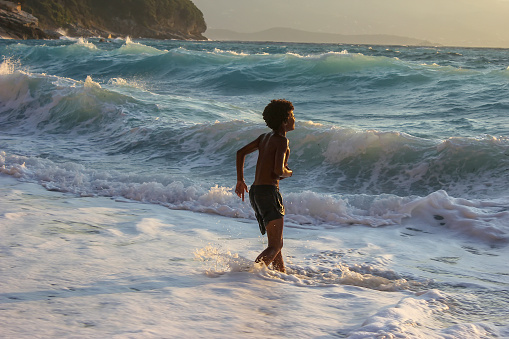 American boy frolics, bathes and swims in the sea. Plays in the spray of sea waves.