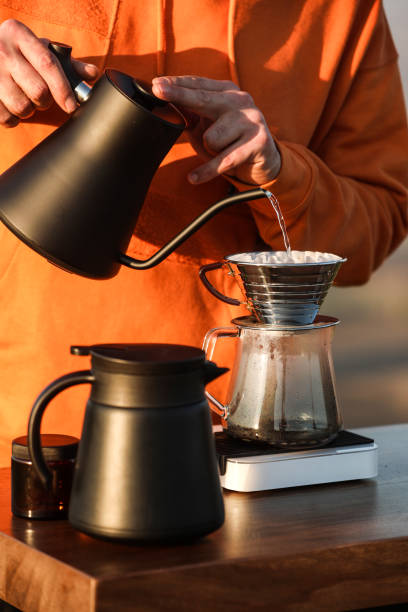 istock Young Man Makes Filter Coffee By Pouring Water From Black Jug On Wooden Table 1356184563