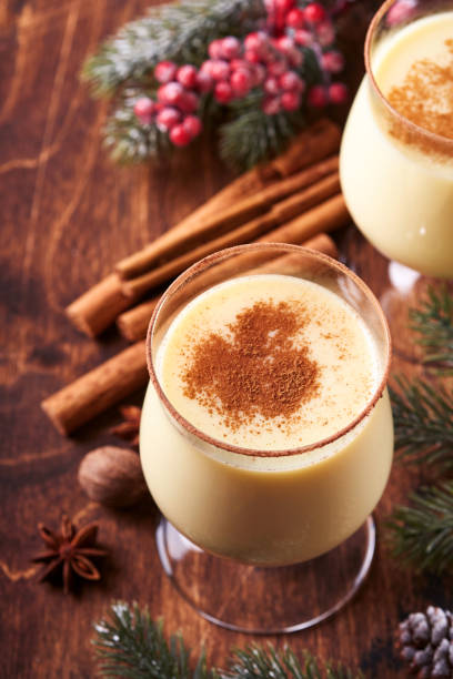 Eggnog Christmas. Delicious winter cocktail milk, rum and cinnamon served in two glasses with shortbread star shape sugar cookies, fir branch over white wooden plank table. Close up. Mock up. stock photo