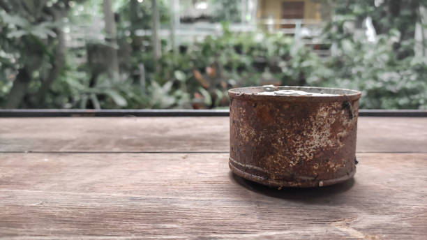 Rusty cans on wooden table and blurred background.