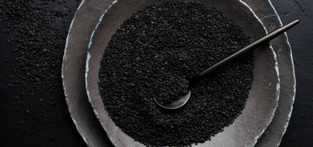 istock Black sesame seeds in black ceramic plates on a dark old vintage background. Rustic style. Top view 1356188957