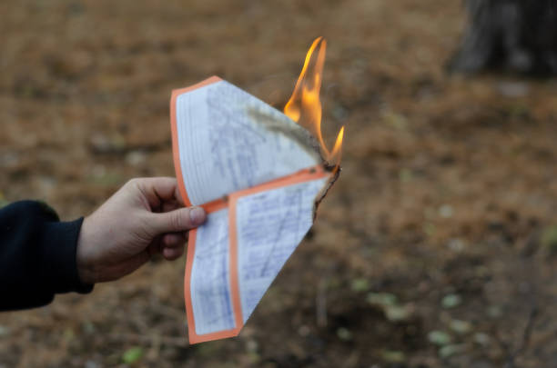 istock A man burns a sheet of paper with handwritten text. 1356189476