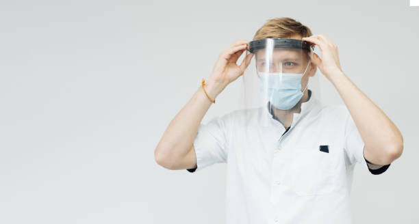 istock Man professional medic put on protective face mask. 1356190114