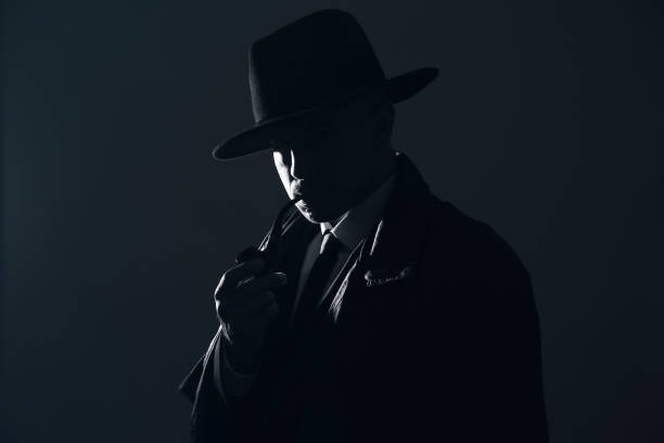 istock Old fashioned detective with smoking pipe on dark background, black and white effect 1356191251