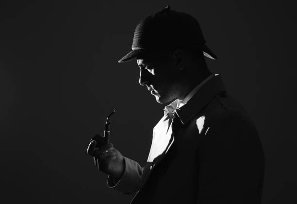 istock Old fashioned detective with smoking pipe on dark background, black and white effect 1356191301