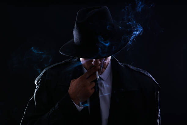 istock Old fashioned detective smoking cigarette on dark background 1356191467