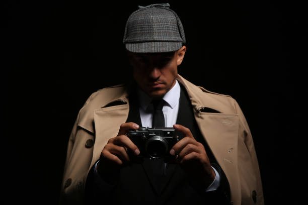istock Old fashioned detective with camera on dark background 1356192156