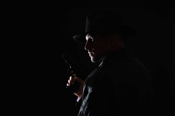 istock Old fashioned detective with gun on dark background. Space for text 1356192241