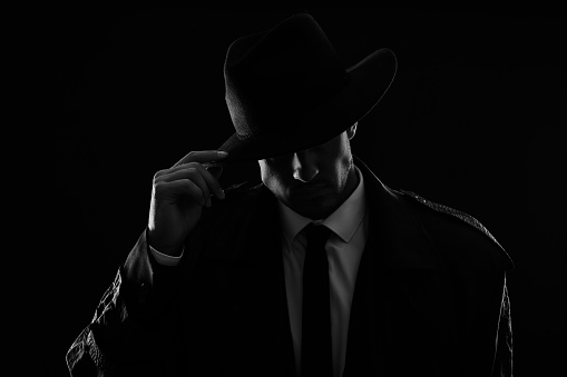 Detective anticuado con sombrero sobre fondo oscuro, efecto blanco y negro photo
