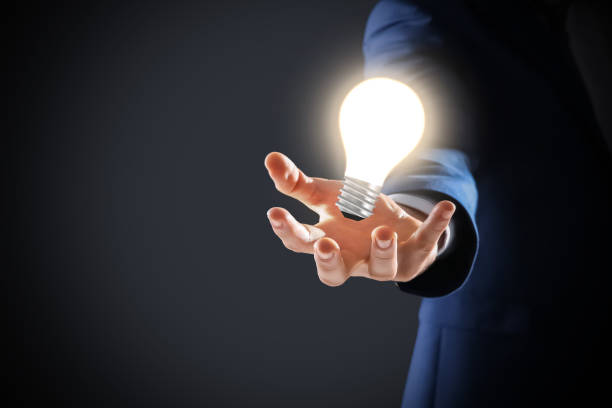istock Idea concept. Businessman demonstrating glowing light bulb illustration on dark background, closeup 1356192610