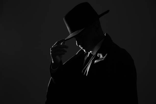 istock Old fashioned detective in hat on dark background, black and white effect 1356192611