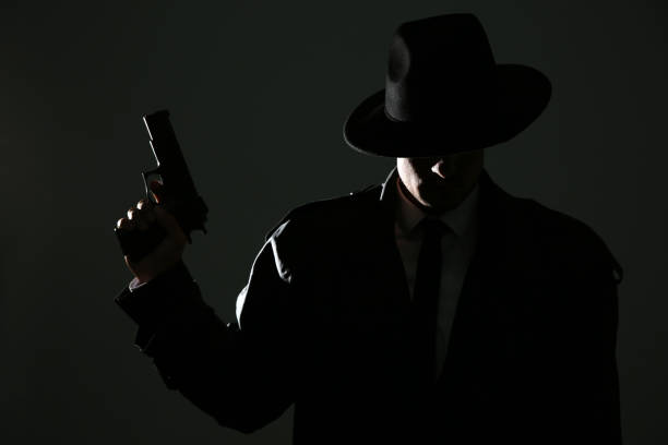 istock Old fashioned detective with gun on dark background 1356192716