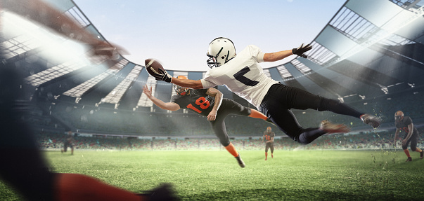 Football match. American football players fight for ball during match at crowded stadium. Sportsmen in uniform with ball jumping and running in excitement. Concept of motion and action, sport, lifestyle.