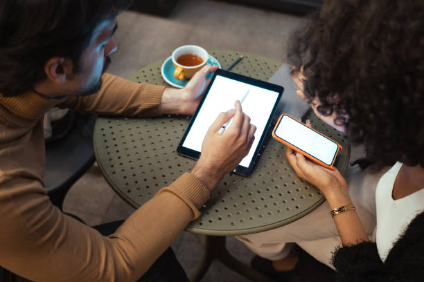 istock Diverse people discussing something while looking at their gadgets at the evening cafe 1356194715