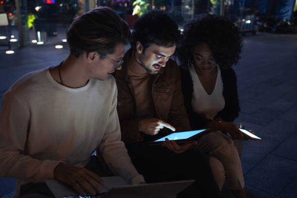 istock Business people looking at tablet screen and smiling while working at night together 1356194840